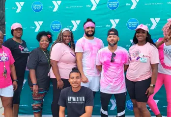 9 men and women standing in front of a YMCA logo backdrop