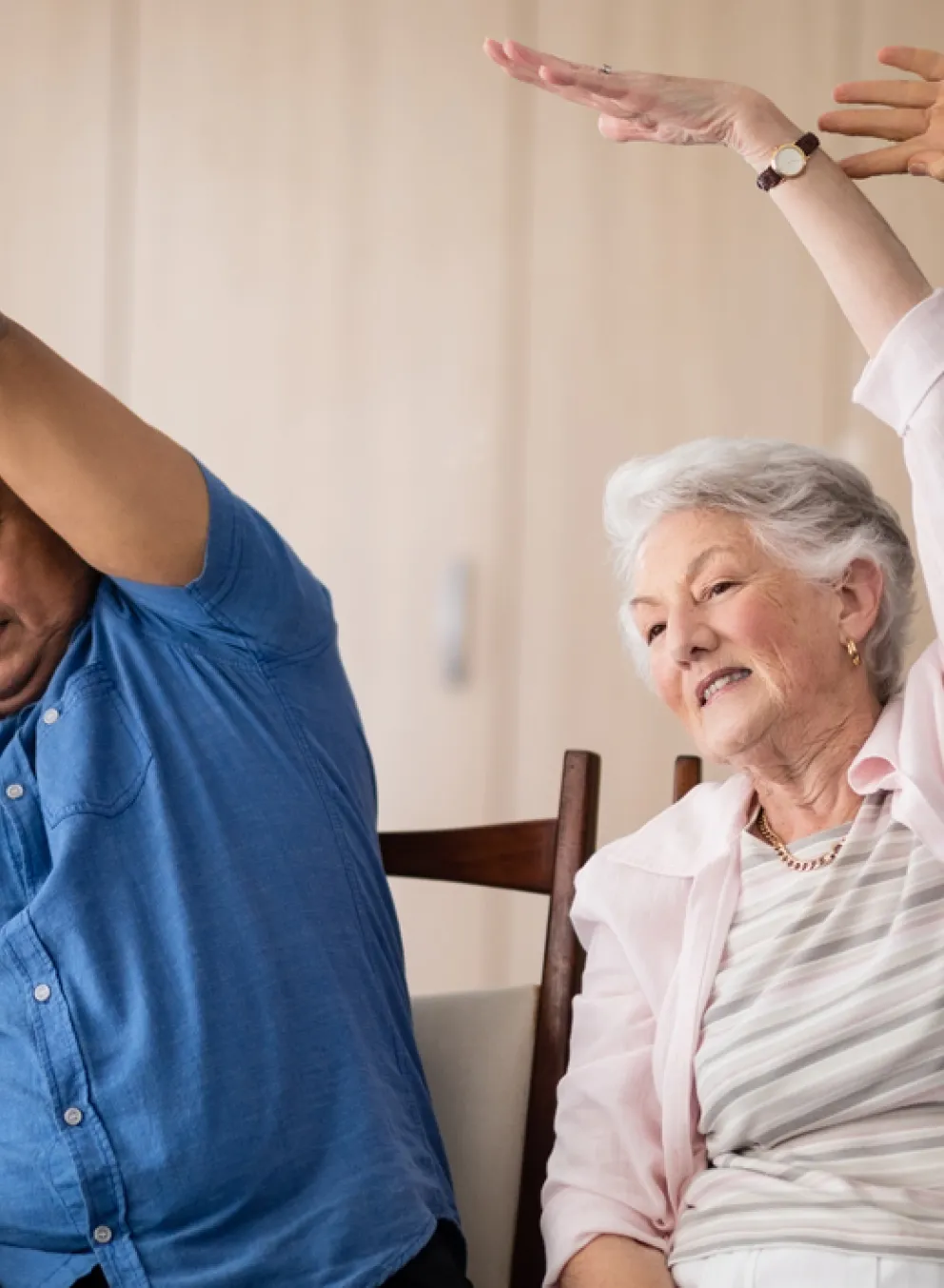 A group of four seniors sitting and reaching one arm to the opposite side.