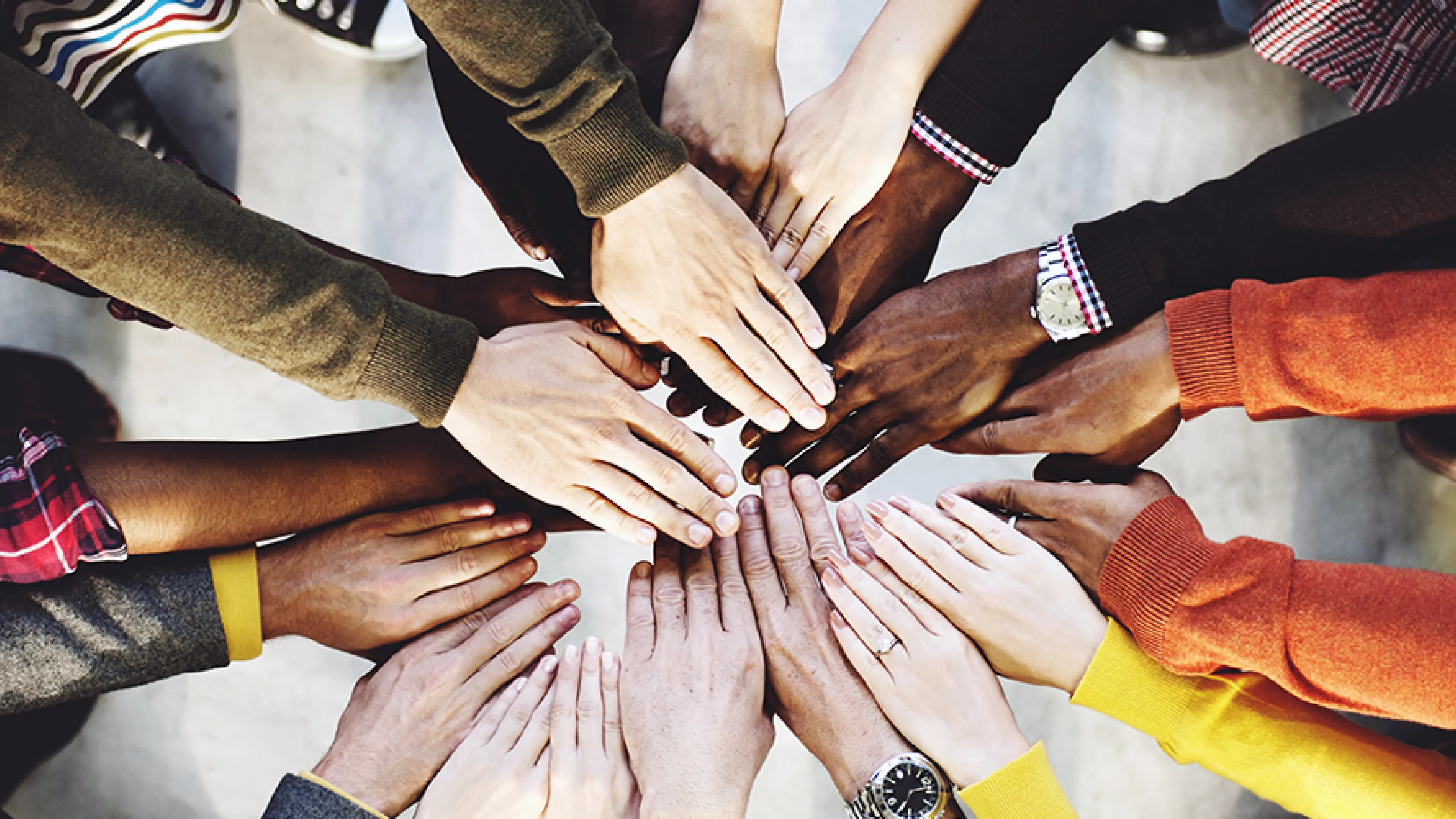 diverse group huddled with hands in the middle