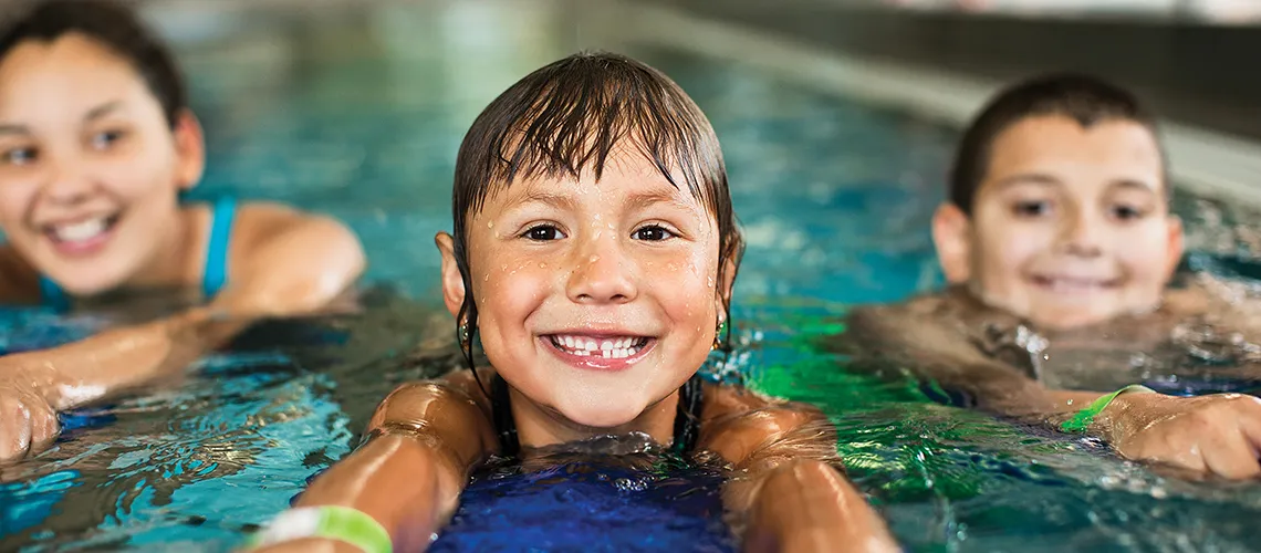 three kids enjoying group swim lessons