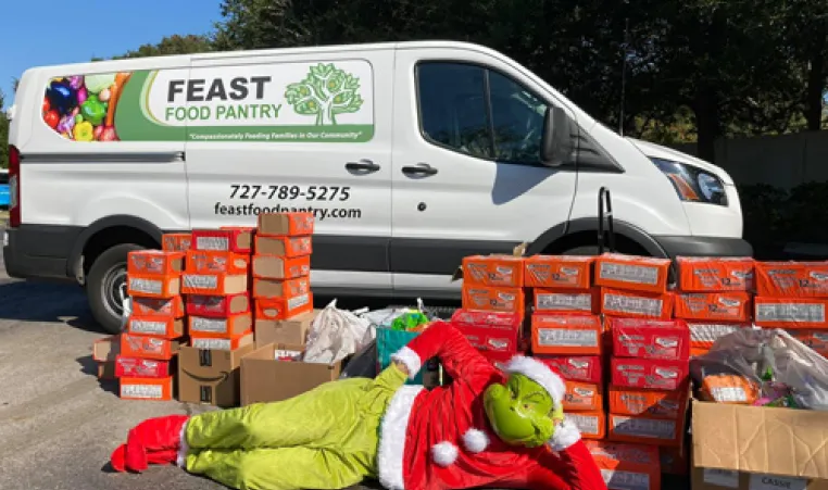 food distribution and the grinch laying on ground in front of boxes of food