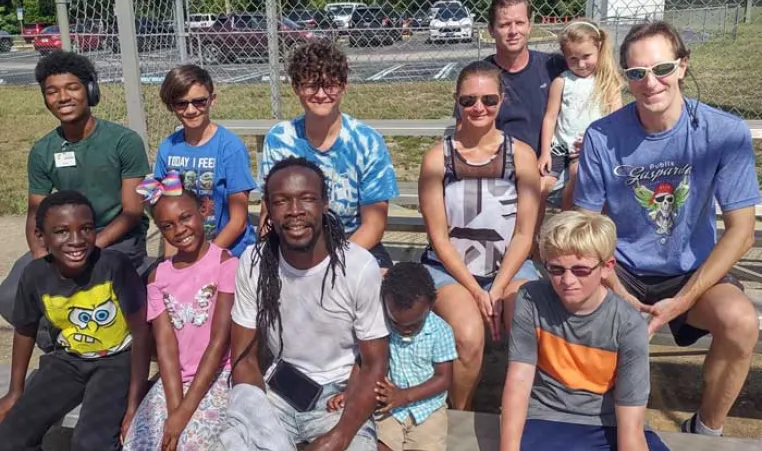 A group of dads and their kids take a break on the bleachers during family kickball.