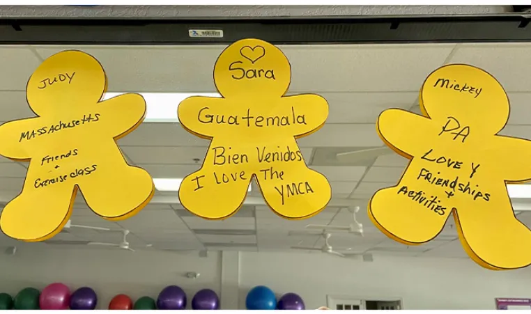 Three yellow human cut outs with black writing stuck on a mirror in exercise room at the Y